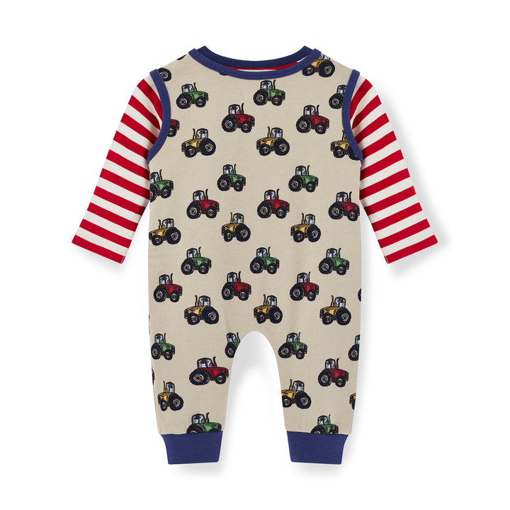 Children's onesie with tractor pattern and red and white striped sleeves on a beige background