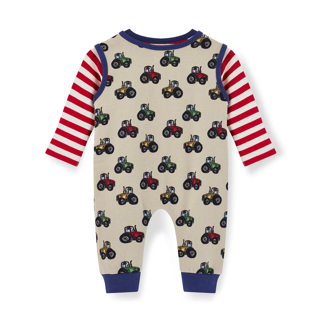 Children's onesie with tractor pattern and red and white striped sleeves on a beige background