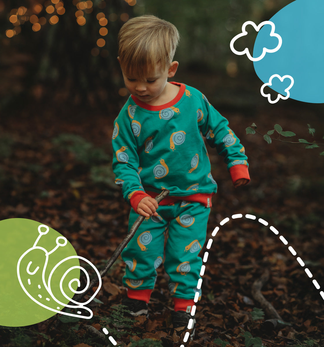 Boy in a forest playing with a stick wearing Lilly and Sid organic cotton snail print matching set.