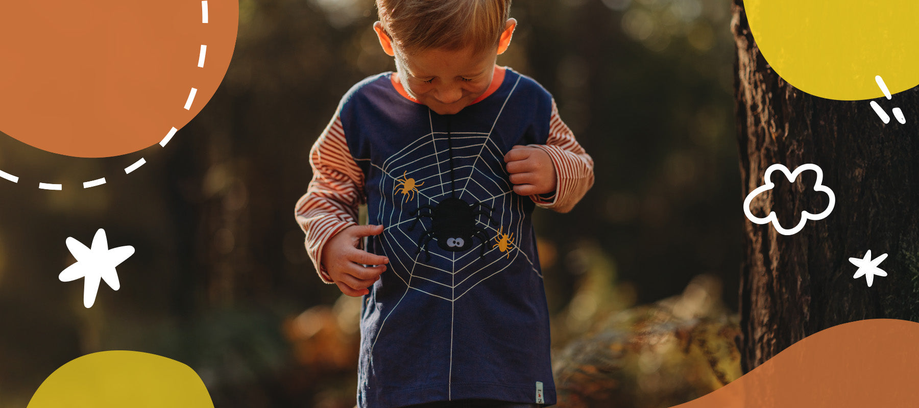 Young Boy in a forest wearing Lilly and Sid Long Stripe Sleeve Spider Web novelty logo top in organic cotton. 