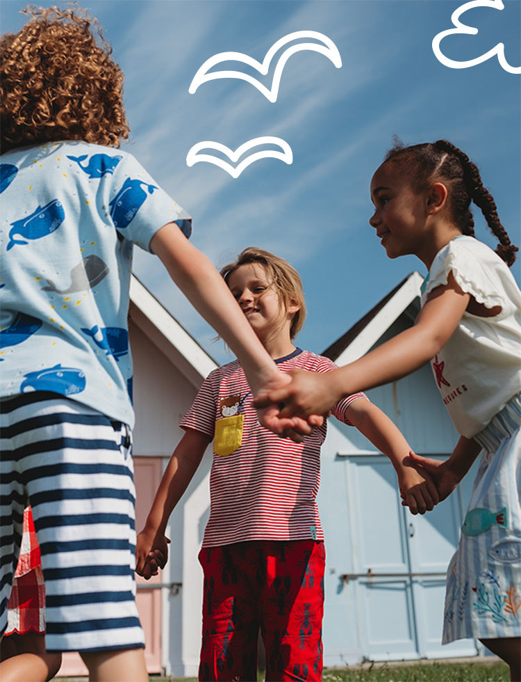 Three children holding hands with a blue sky and white birds in the background