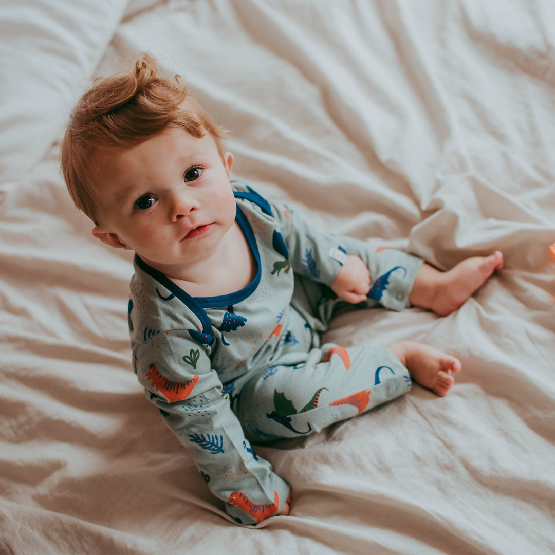 Baby boy wearing sustainable organic cotton dino baby playsuit