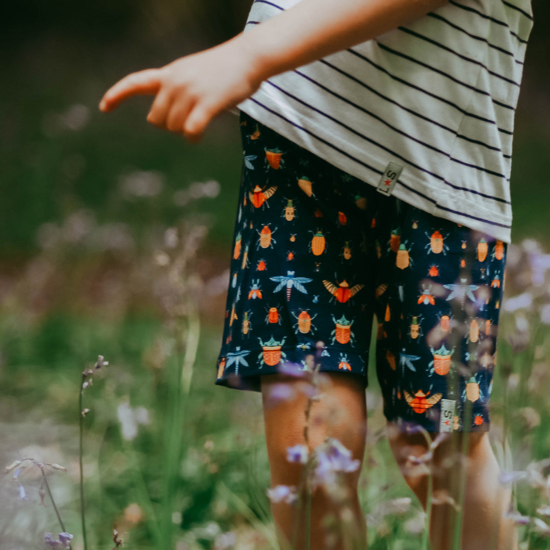 a boy wearing bug pattern shorts